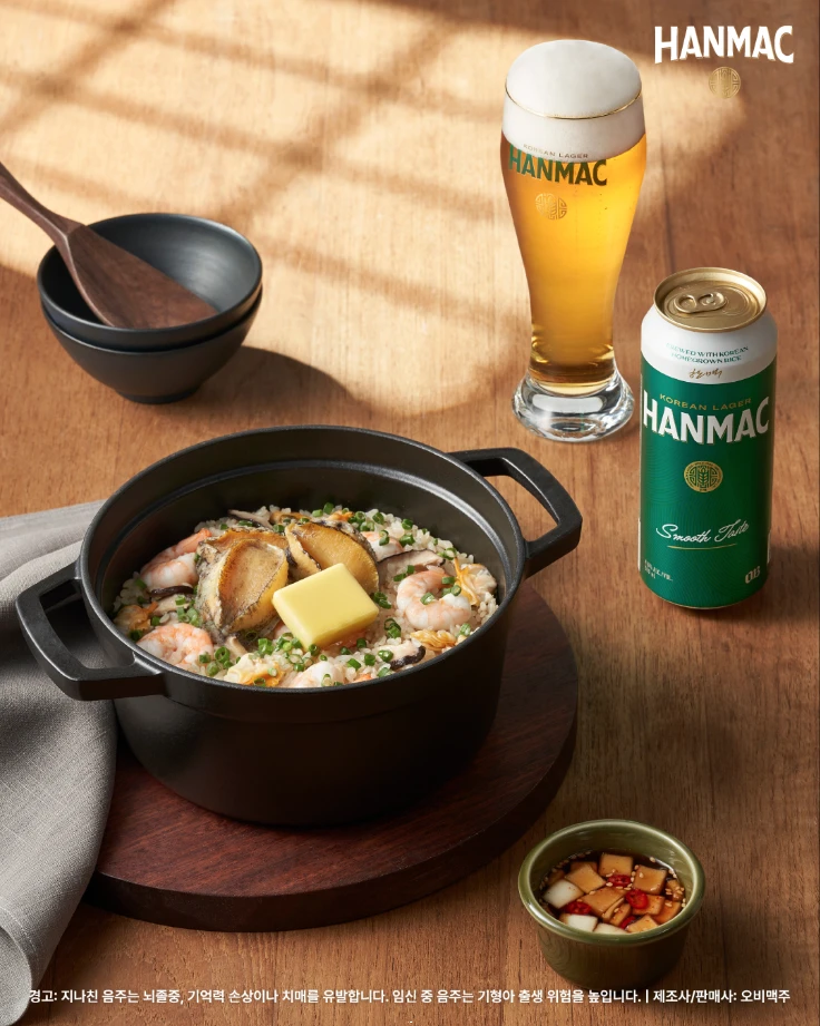 한맥 음식 디스커버리 세번째 에피소드 버터 해물 솥밥 플레이팅과 500ml 맥주 캔이 있습니다.