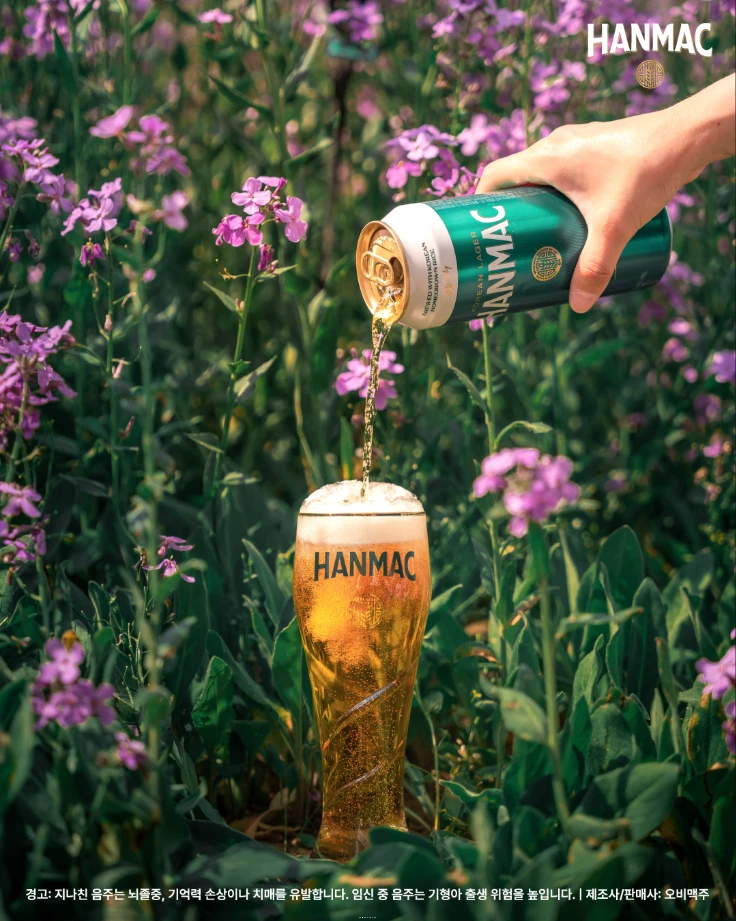 한맥 장소 디스커버리 두번째 에피소드 고즈넉한 전국 명상 스팟의 두번째 영천 생태지구공원에 있는 청유채 꽃밭에서 한맥 500ml 맥주를 전용잔에 따르고 있습니다.